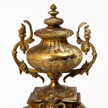 A mantle clock and a pair of candelabra, Louis XVI style, ca 1900.