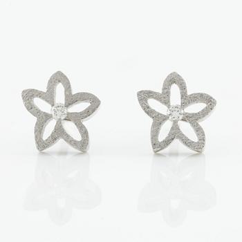 Ole Lynggard ett par örhängen i form av blommor.