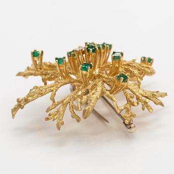 An 18K gold brooch with a diamond ca. 0.06 ct and emeralds.