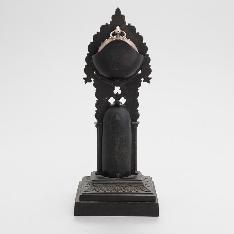 A neo-gothic cast iron pocket watch stand with a pocket watch. 19th century.