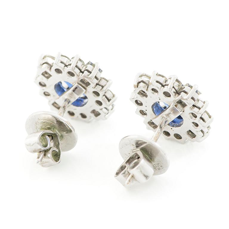 A pair of 14K gold earrings with faceted sapphires and round brilliant- and princess-cut diamonds.