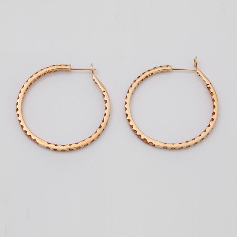 A pair of orange-yellow sapphire hoop earrings.