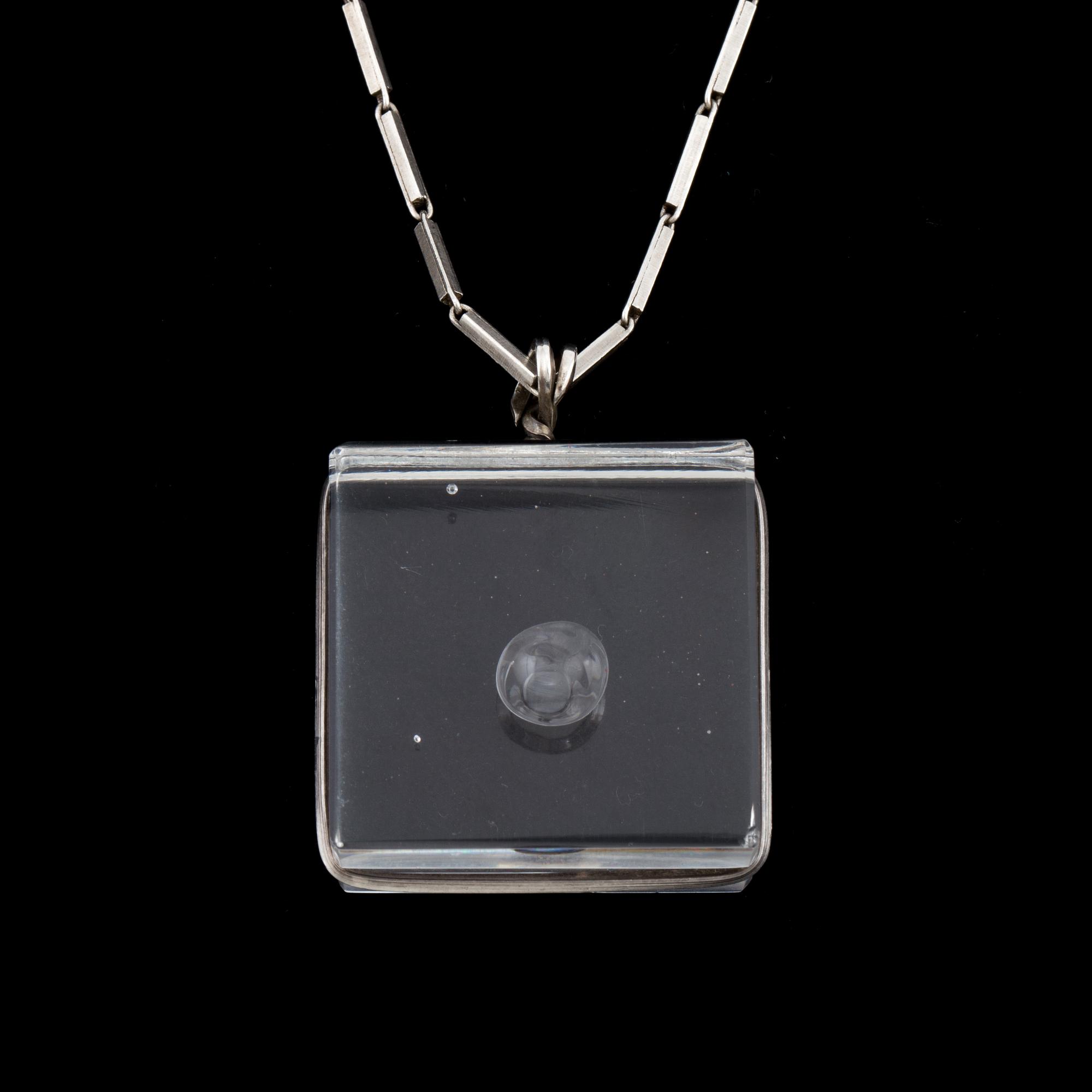 A glass pendant designed by Gunnar Cyrén and a silver necklace.