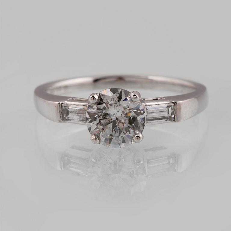 RING, 18K vitguld med briljantslipad diamant ca 1.05 ct samt 2 baguettslipade diamanter ca 0.17 ct. Vikt 3,2 gram.