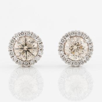 A pair of 18K gold earrings with round brilliant-cut diamonds.