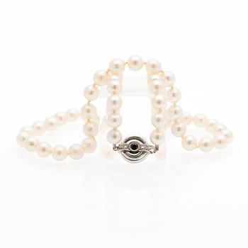 Pearl necklace, white gold clasp set with diamonds and a sapphire.