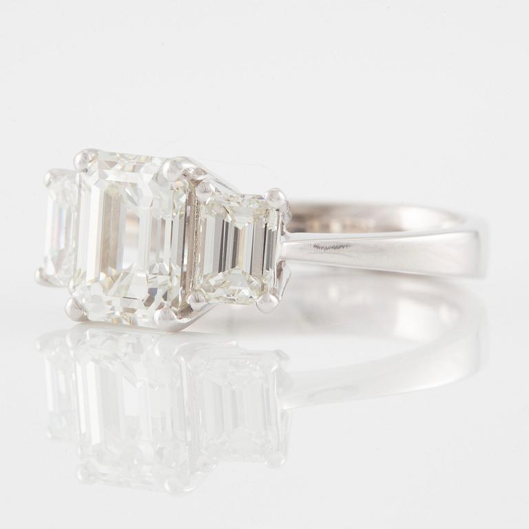 An 18K white gold ring set with three emerald-cut diamonds.