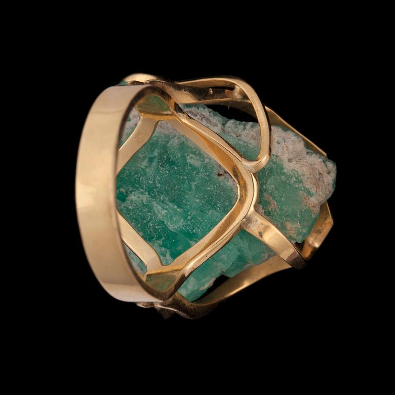 A gold ring set with an un-cut stone, probably emerald.