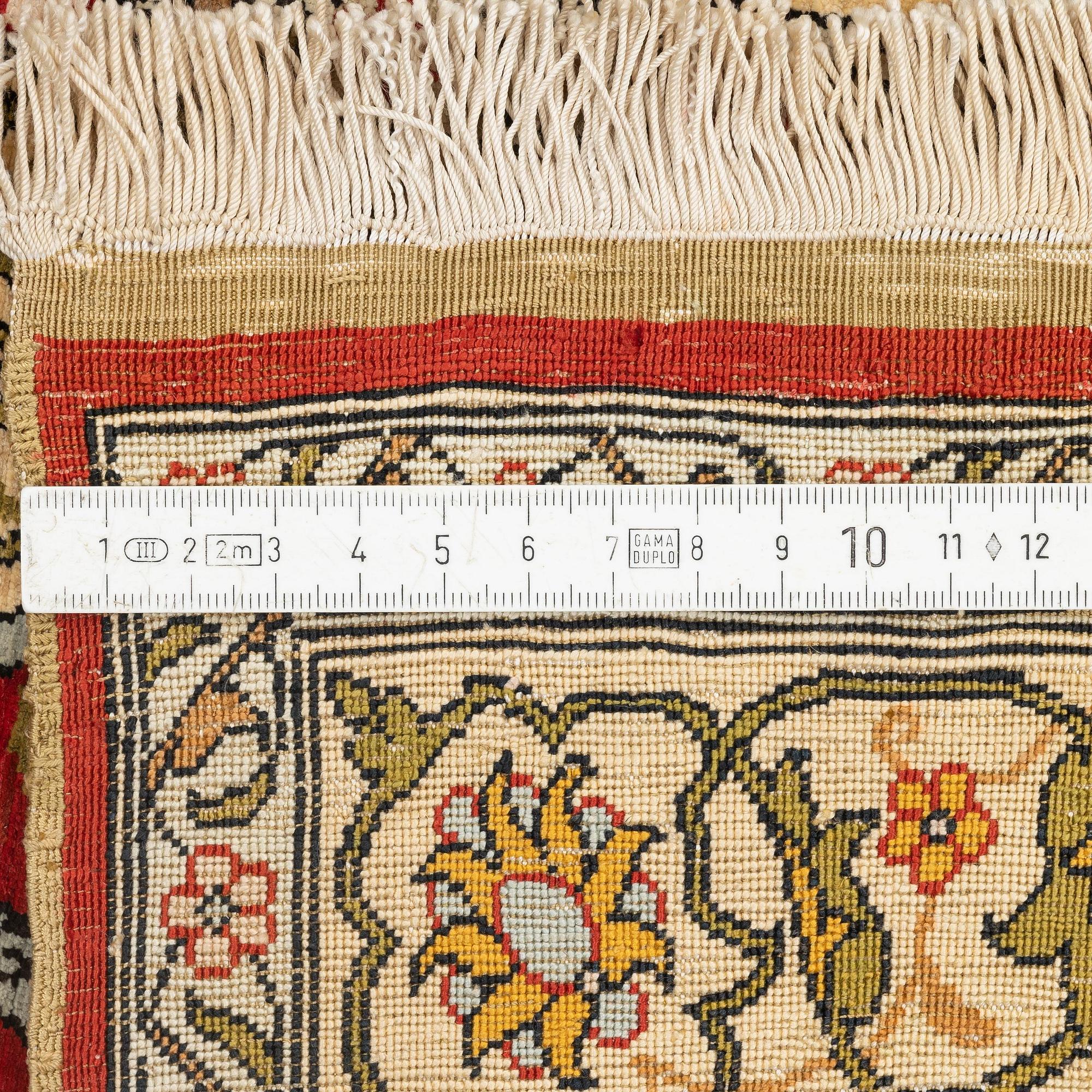 A silk and metal Hereke rug, c. 86 x 52 cm.