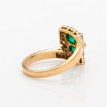 An 18K gold ring with emeralds and diamonds.