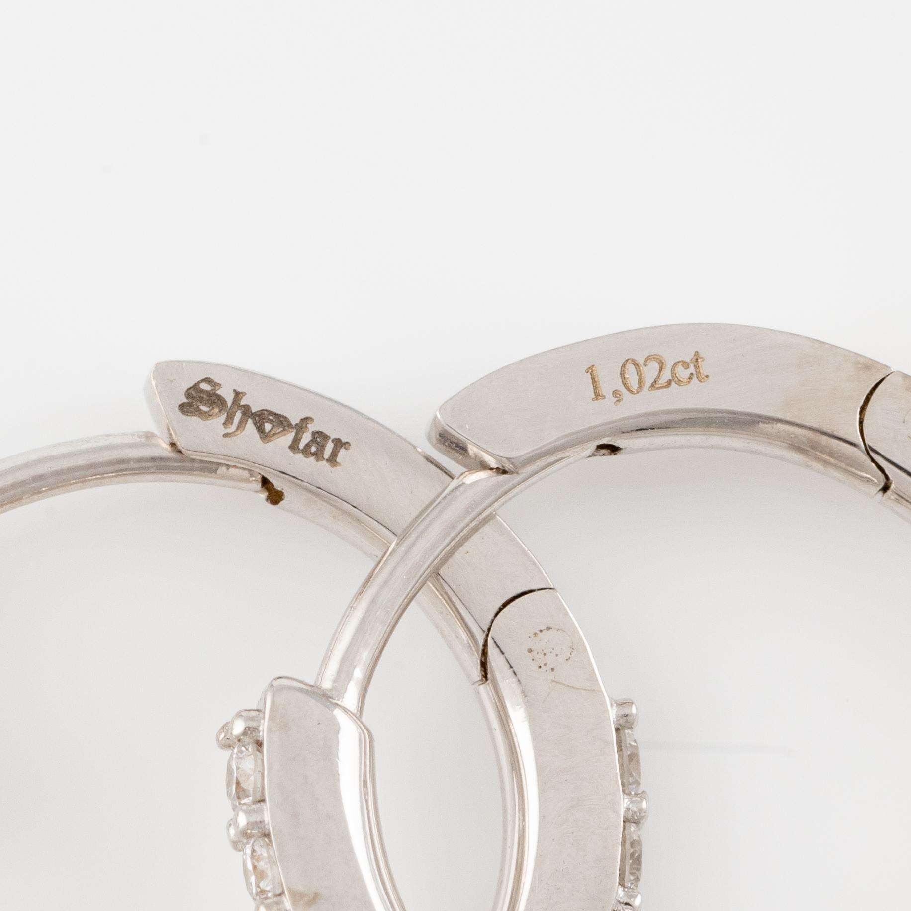 A pair of 18K gold earrings with round brilliant-cut diamonds.