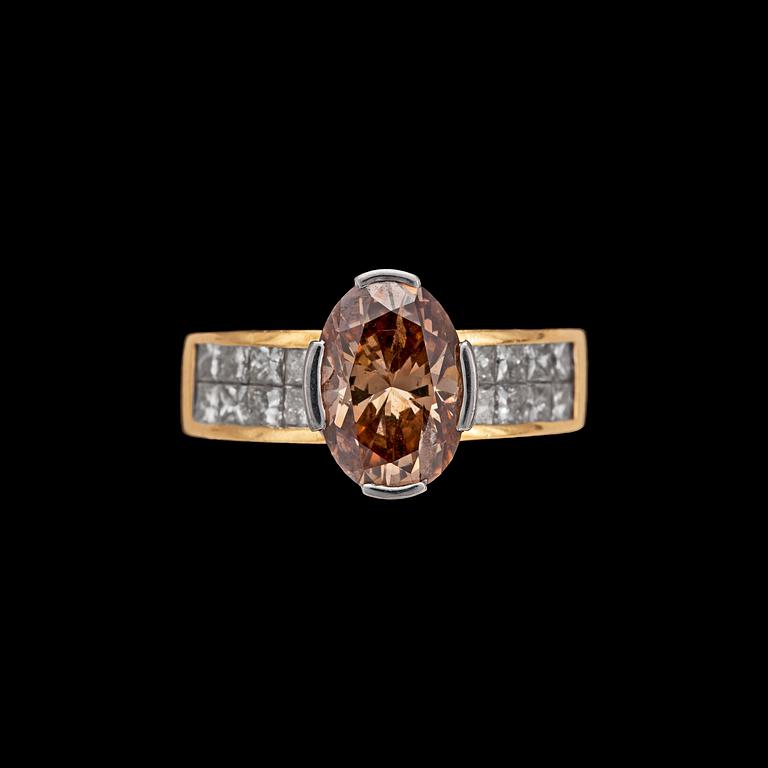 A cognacs coloured oval cut diamond 2.78 cts, set with princess cut diamonds, tot. 1 cts.