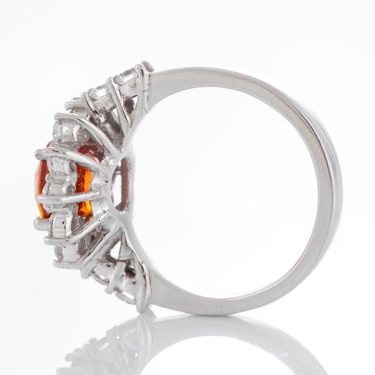 A ring set with a faceted spessartine garnet and round brilliant-cut diamonds.