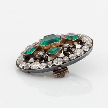 A gold and silver brooch set with faceted emeralds and old- and rose-cut diamonds.