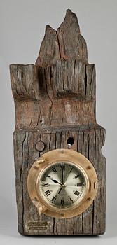 VÄGGUR innfattat i mässing på träbalk.