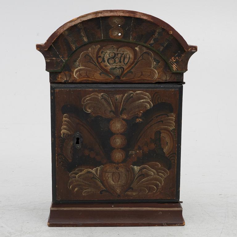 A hanging cabinet, dated 1870.
