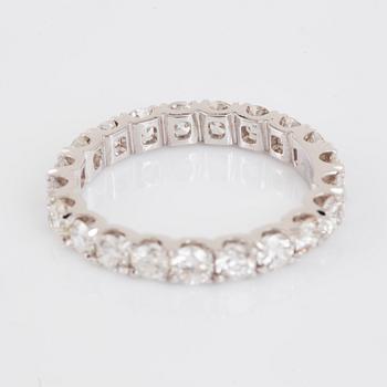 An 18K gold eternity ring set with round brilliant-cut diamonds.