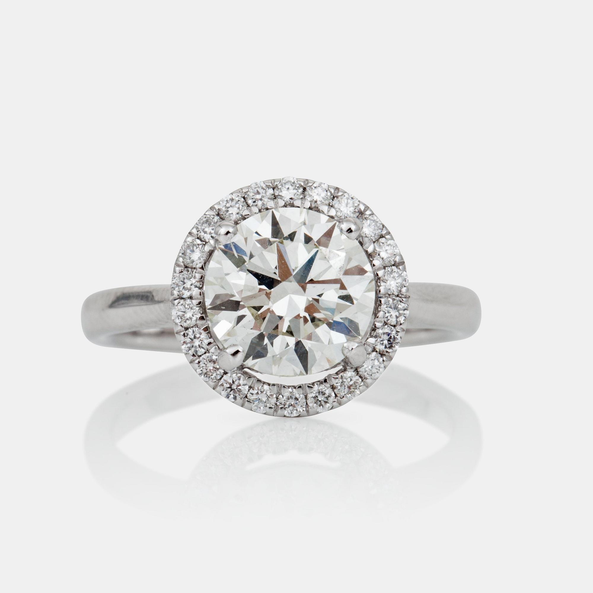 A brilliant-cut diamond, circa 2.00 cts, K/VS surrounded by pavé-set diamonds.