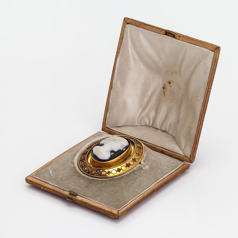 An 18K gold brooch with an onyx cameo and rubies.