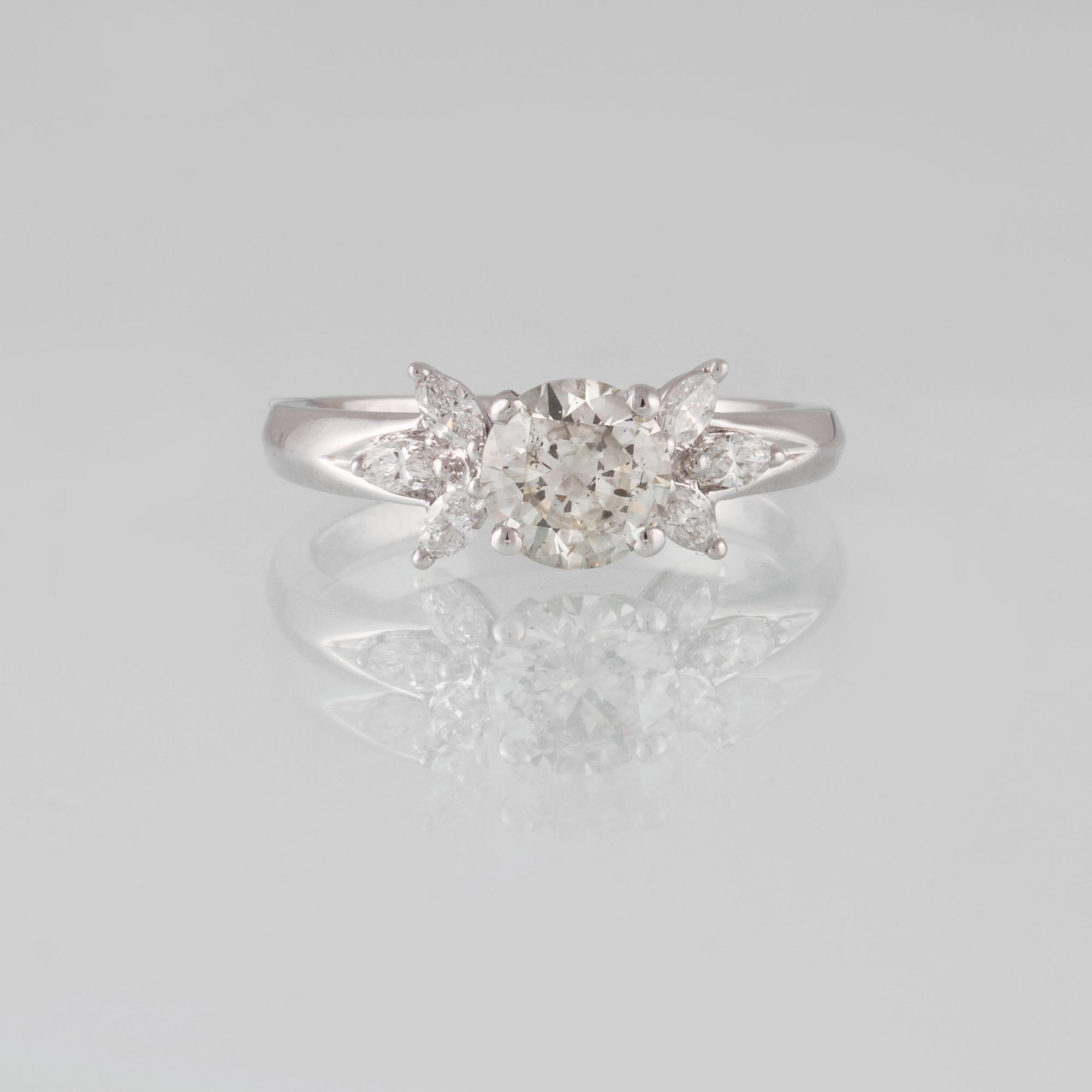 RING, 18K vitguld med briljantslipad diamant ca 1.11 ct samt 6 navetteslipade diamanter 0.26 ct. Vikt 4,2 gram.