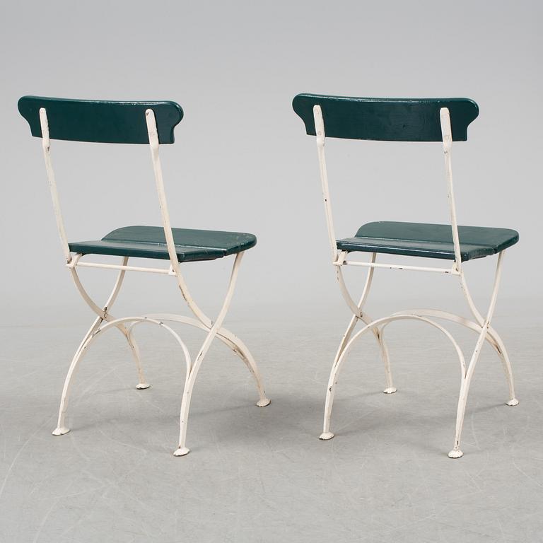 A pair of cast iron chais with wooden seats and a cast iron table, early 20th century.