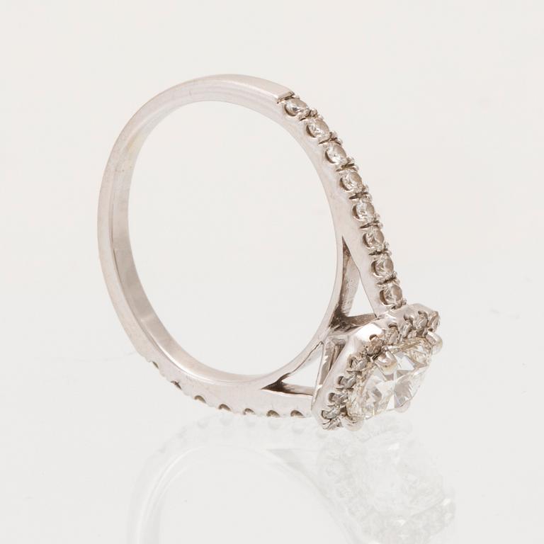 An 18K white gold ring set with a modified cushion-cut diamond and round brilliant-cut diamonds.