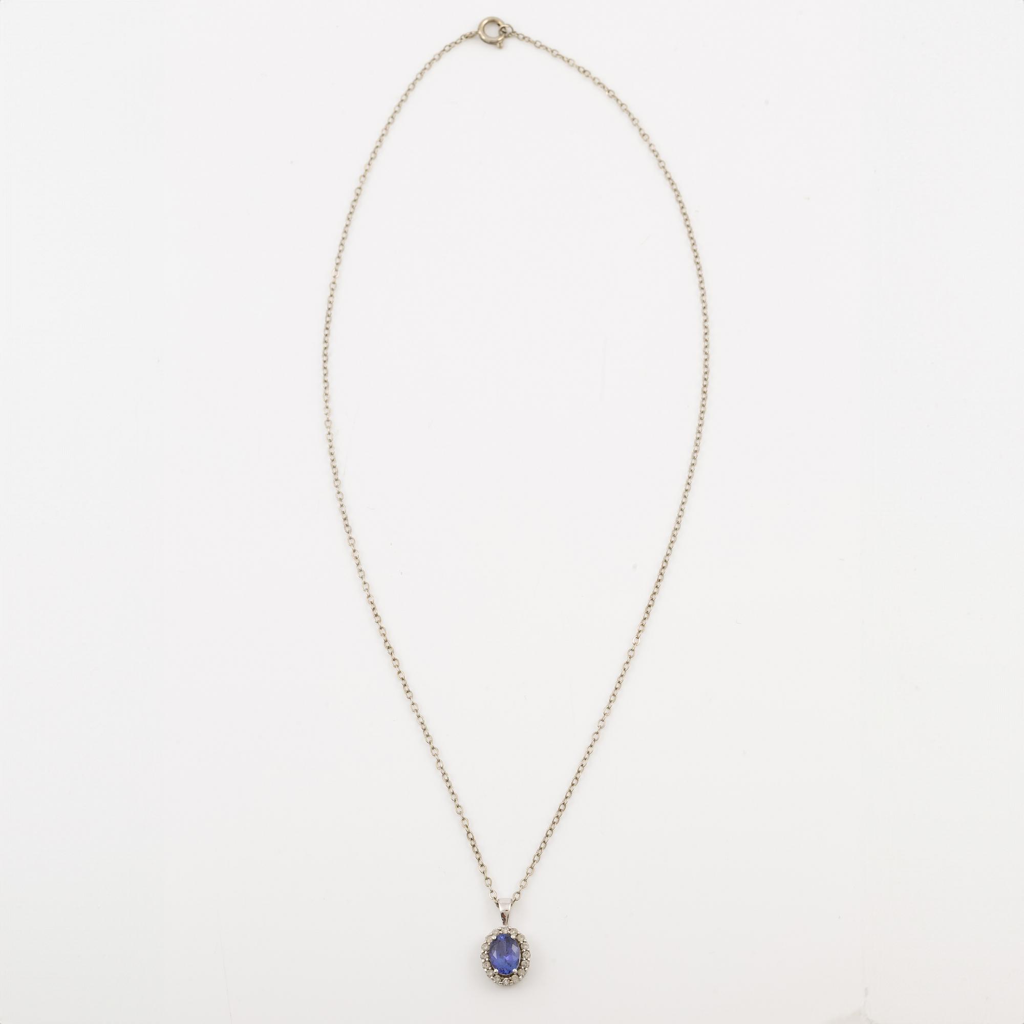 Pendant in 14K white gold set with a faceted tanzanite and round brilliant-cut diamonds.