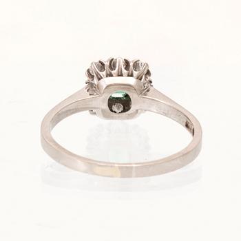 An 18K white gold ring set with a step cut emerald and round brilliant cut diamonds, Stockholm 1964.