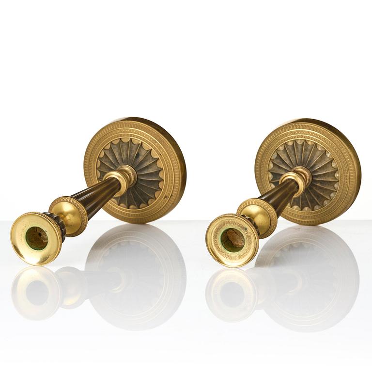 A pair of French Empire patinated and ormolu candlesticks, early 19th century.