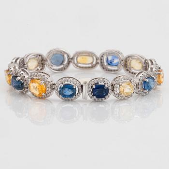 An 18K white gold bracelet set with faceted blue and yellow sapphires with a total weight of 25.80 cts.