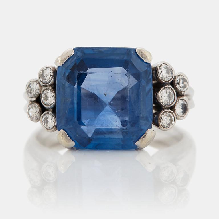 An 18K white gold ring set with a faceted sapphire and round brilliant-cut diamonds.