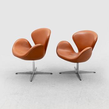 Arne Jacobsen, a pair of "Svanen" (Swan) leather armchairs for Fritz Hansen, Denmark, dated 1999 and 2002.