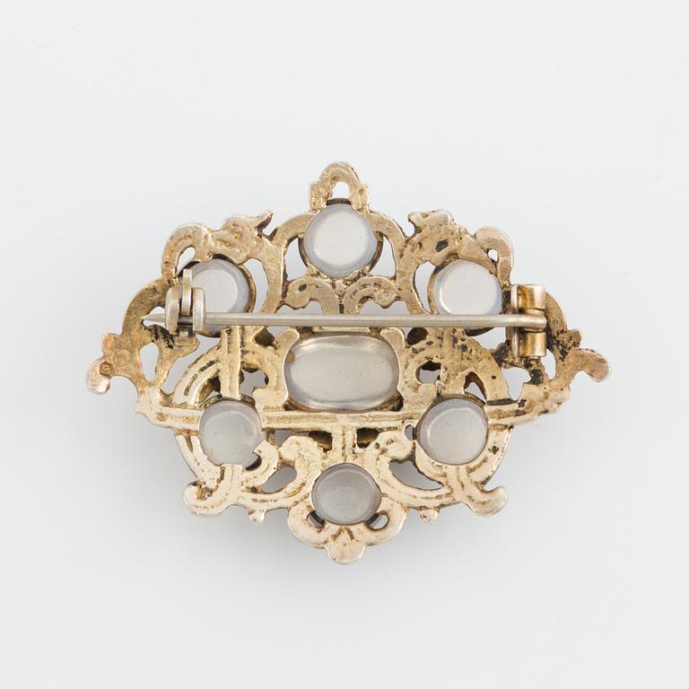 A brooch set with cabochon-cut moonstones.