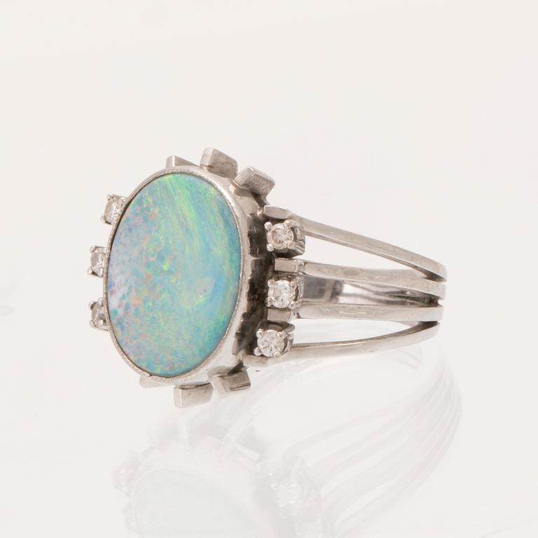 A 14K white gold ring set with an opal doublet or triplet and round brilliant-cut diamonds.