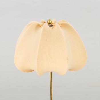 A brass floor light with white fabric lamp-shade.