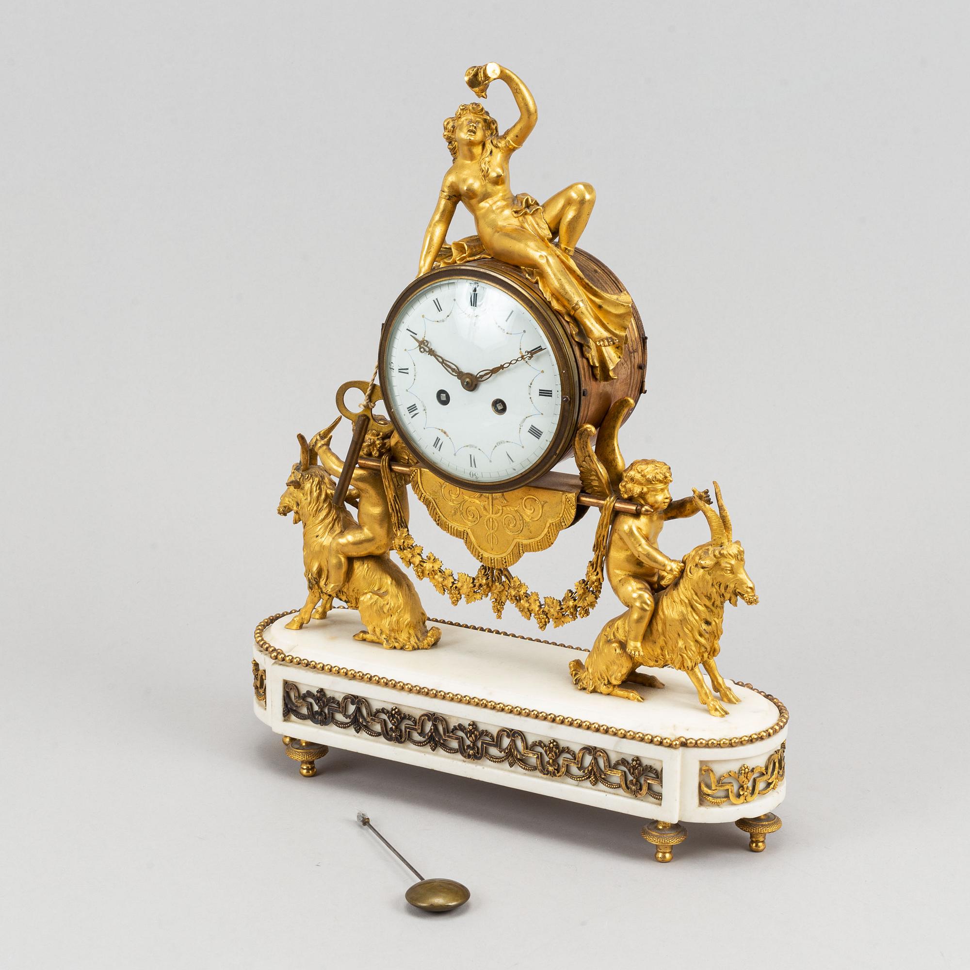 A marble and gilt bronze mantle clock in Louis XVI style, decorated with grapes, putti and a bacchant, 19th century.