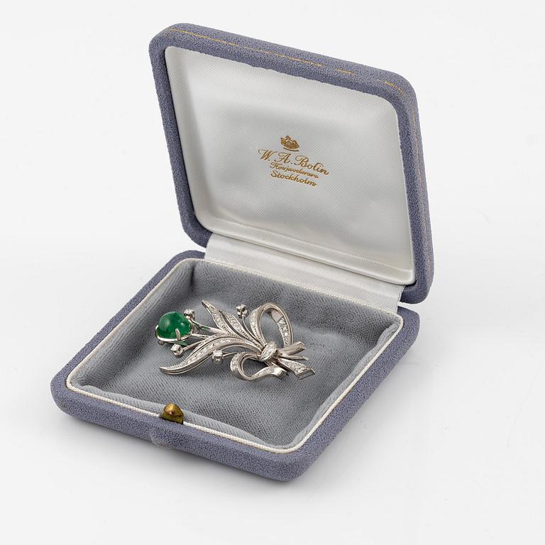 A brooch in 18K white gold with a cabochon-cut emerald.