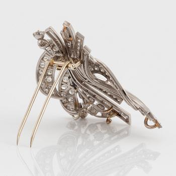 A platinum and 18K gold brooch set with round brilliant- and baguette-cut diamonds.