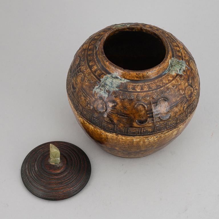 A ceramic glazed jar with wooden cover and a nephrite knob, Qing dynasty, 19th century.