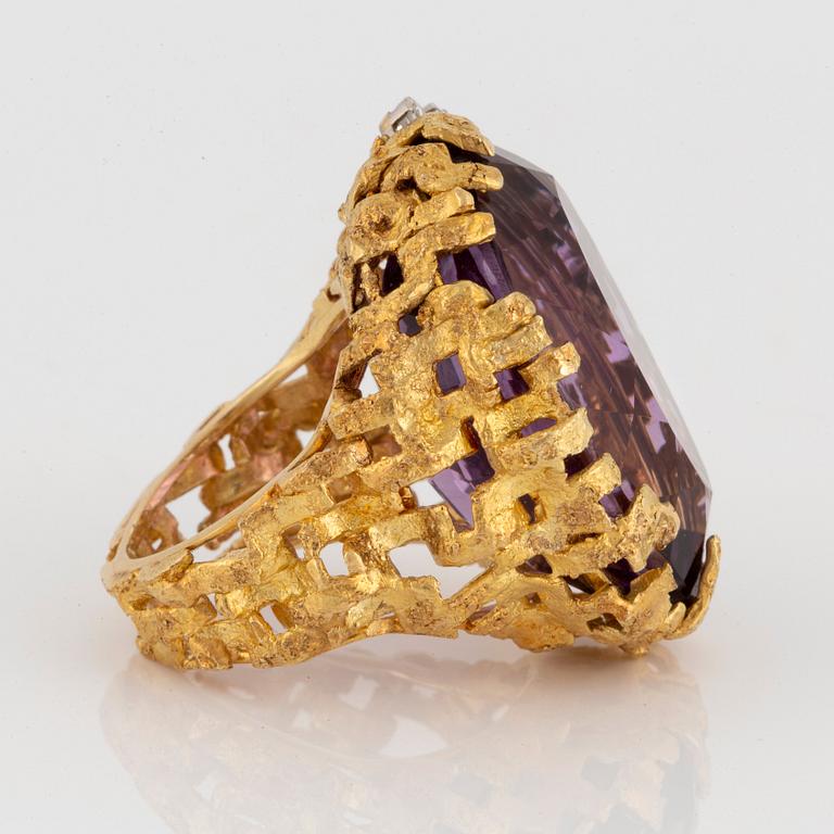 An 18K gold and platinum ring set with an amethyst and round brilliant-cut diamonds.