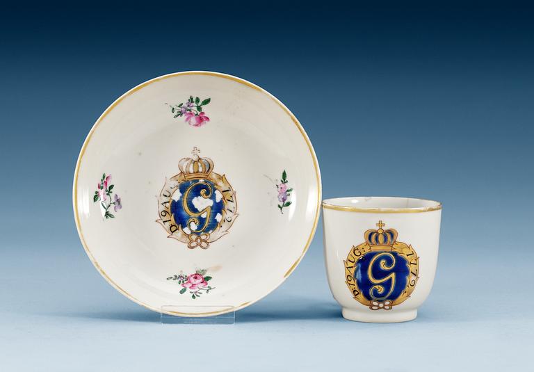 A famille rose armorial cup and stand with the crowned monogram of the Swedish King Gustavus III and the date 19th of August 1772.