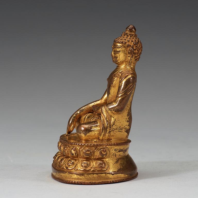 A gilt Tibetan bronze figure of Buddha, 16th Century or older.