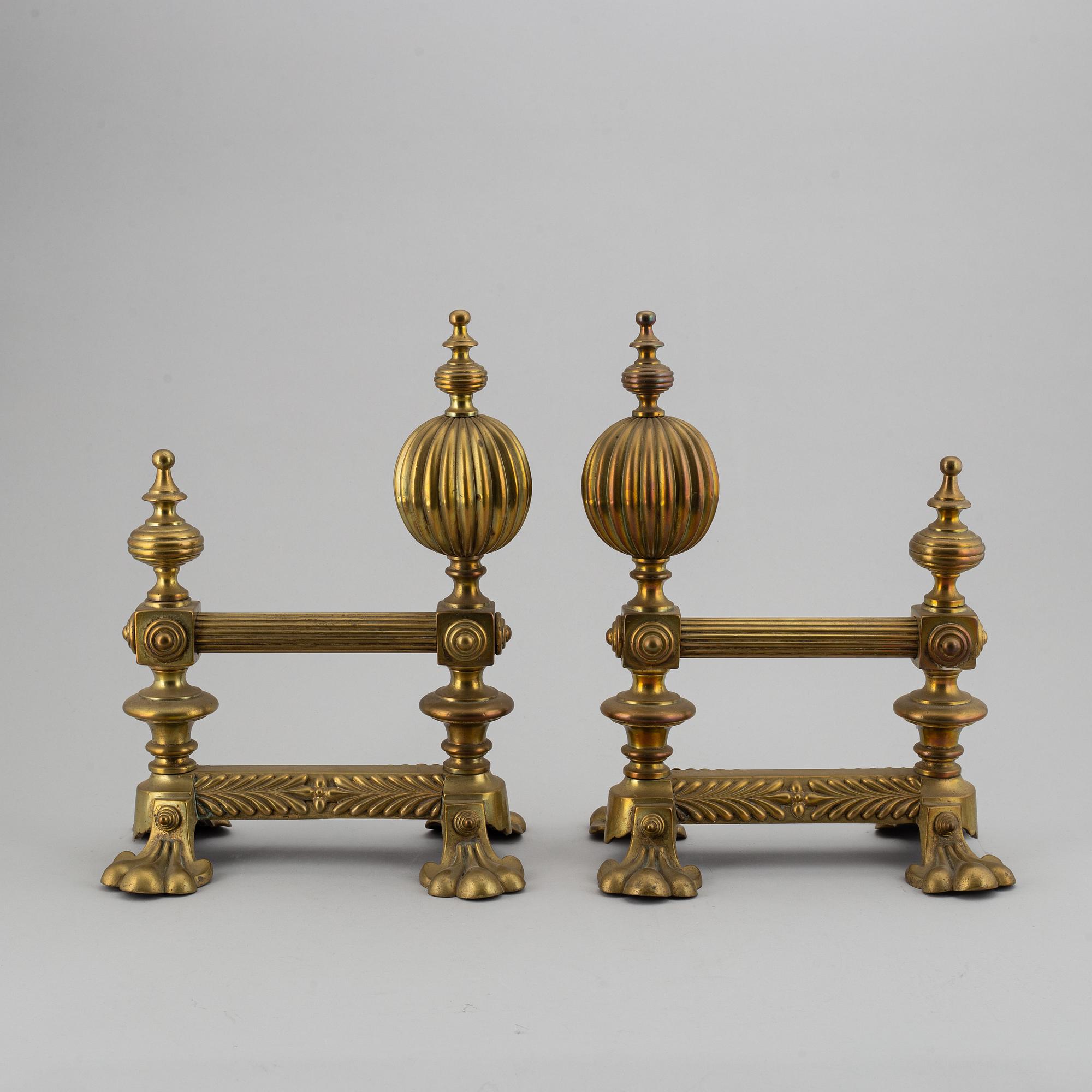 A pair of brass fire dogs and a brass fireplace poker set.