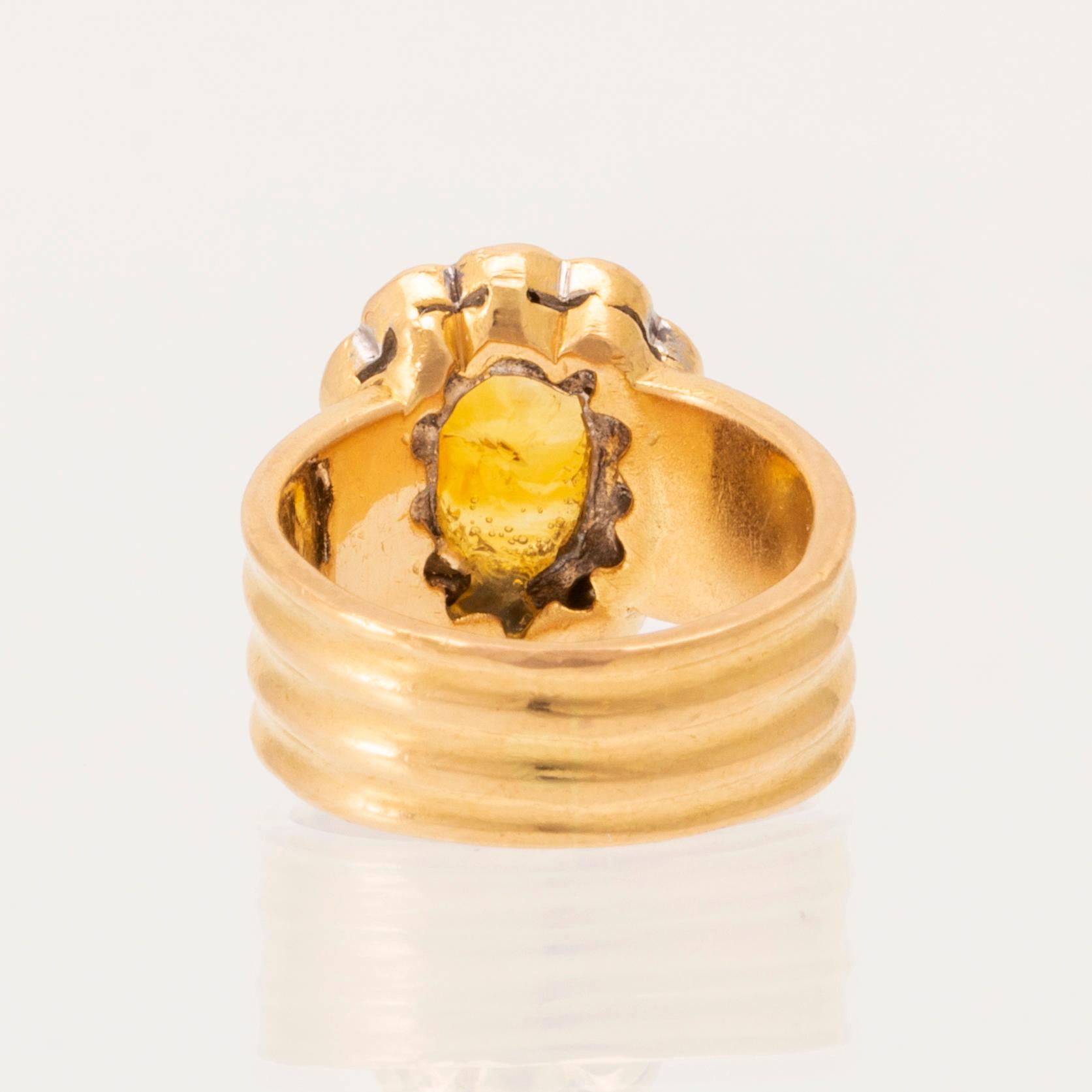 A 22K gold carmosé ring with an oval faceted yellow sapphire and round brilliant-cut diamonds.
