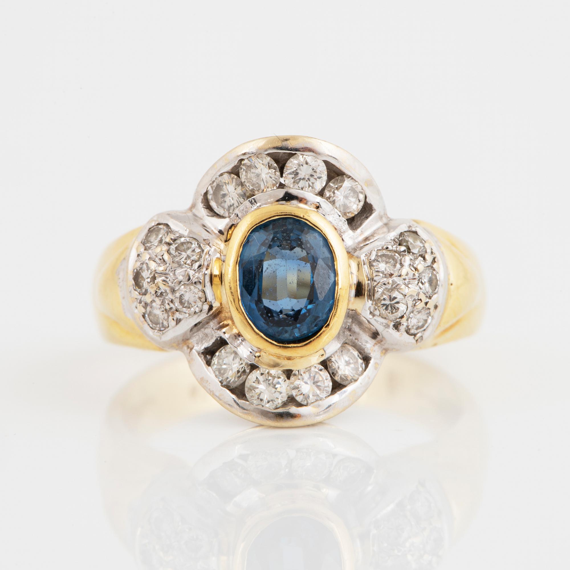 An 18K gold ring set with a synthetic sapphire and round brilliant-cut diamonds.