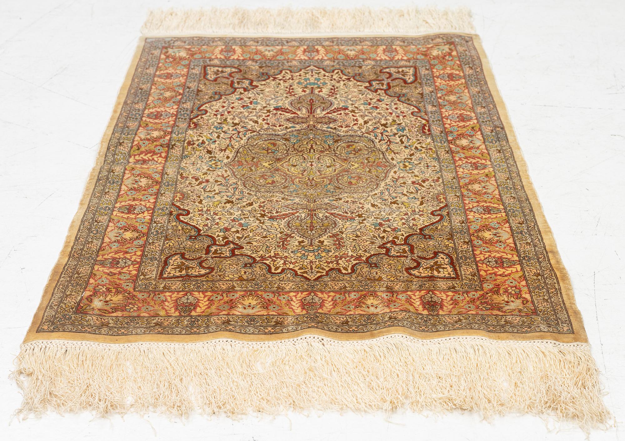 A silk Hereke rug, c. 85 x 55 cm.