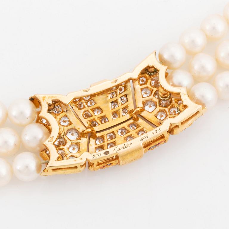 A Cartier triple strand cultured pearl necklace with an 18K gold clasp set with round brilliant-cut diamonds.