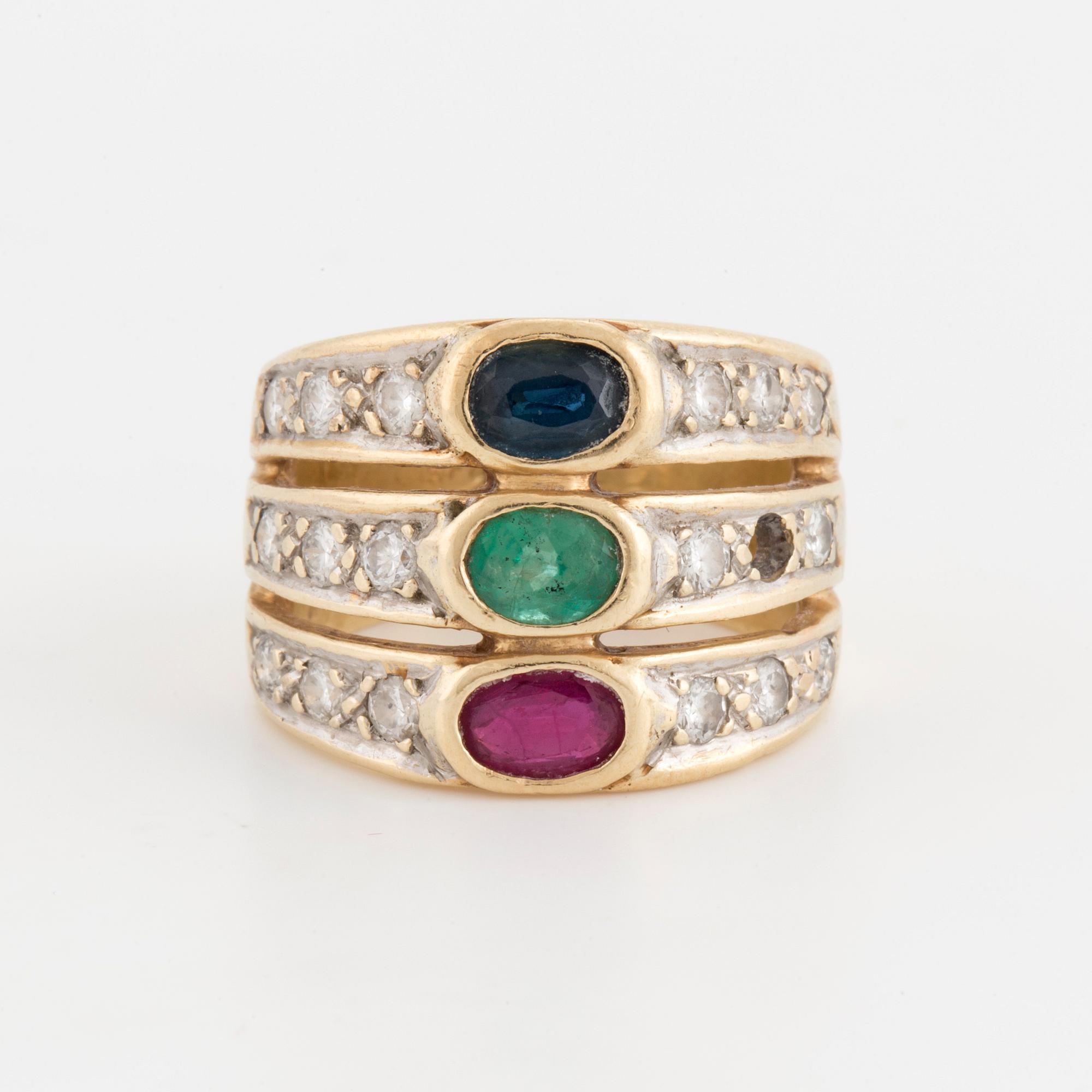 An oval cut ruby, sapphire and emerald ring, surrounded by brilliant cut diamonds.
