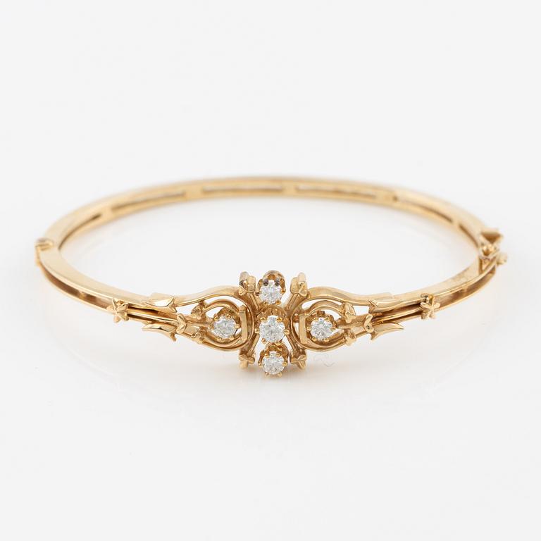 A bangle in 14K gold with round brilliant-cut diamonds.