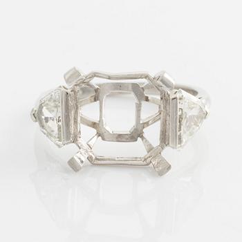 A platinum ring with and empty setting and with two triangular step cut diamonds.